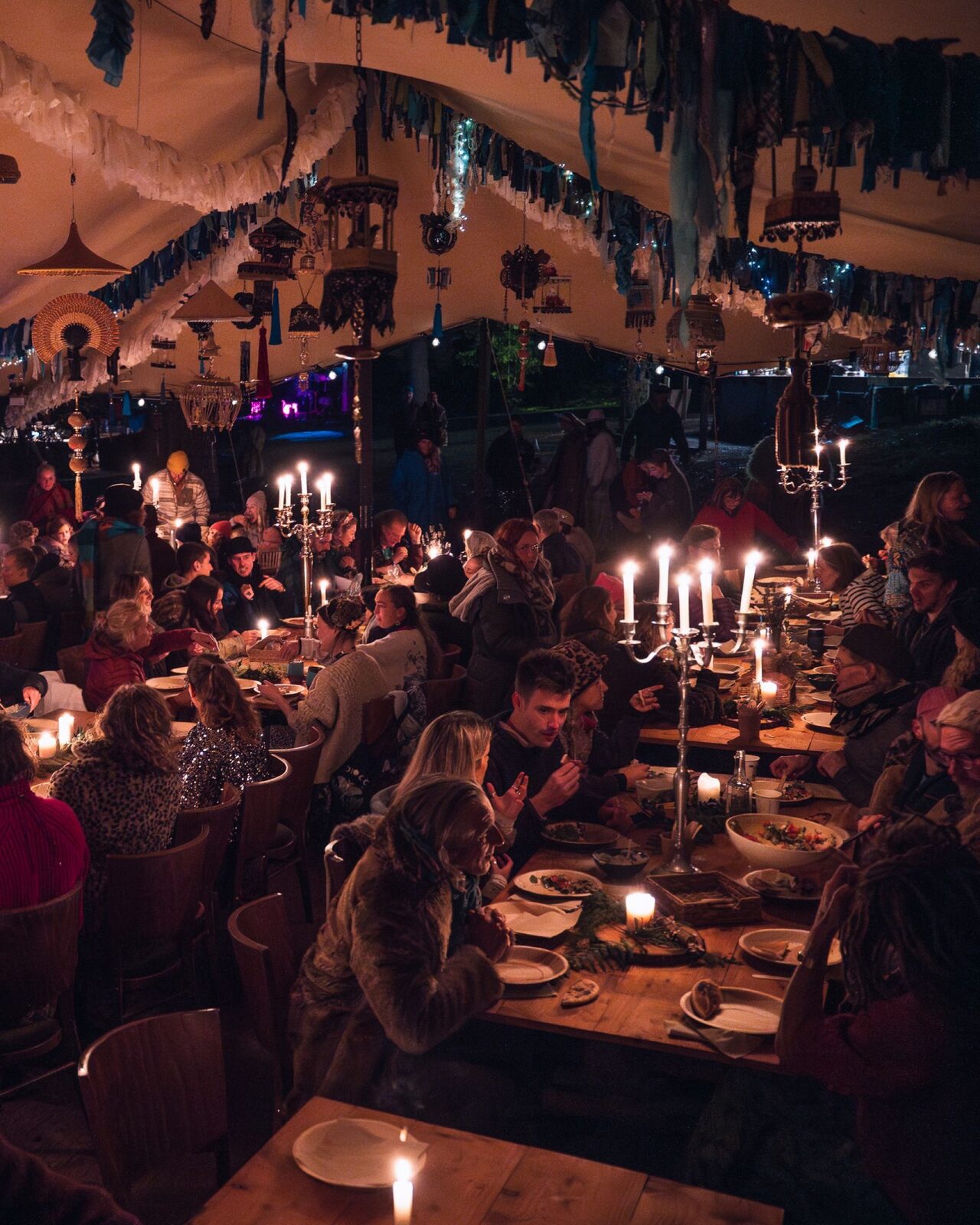 Long candlelit banquet table glowing under canvas at night