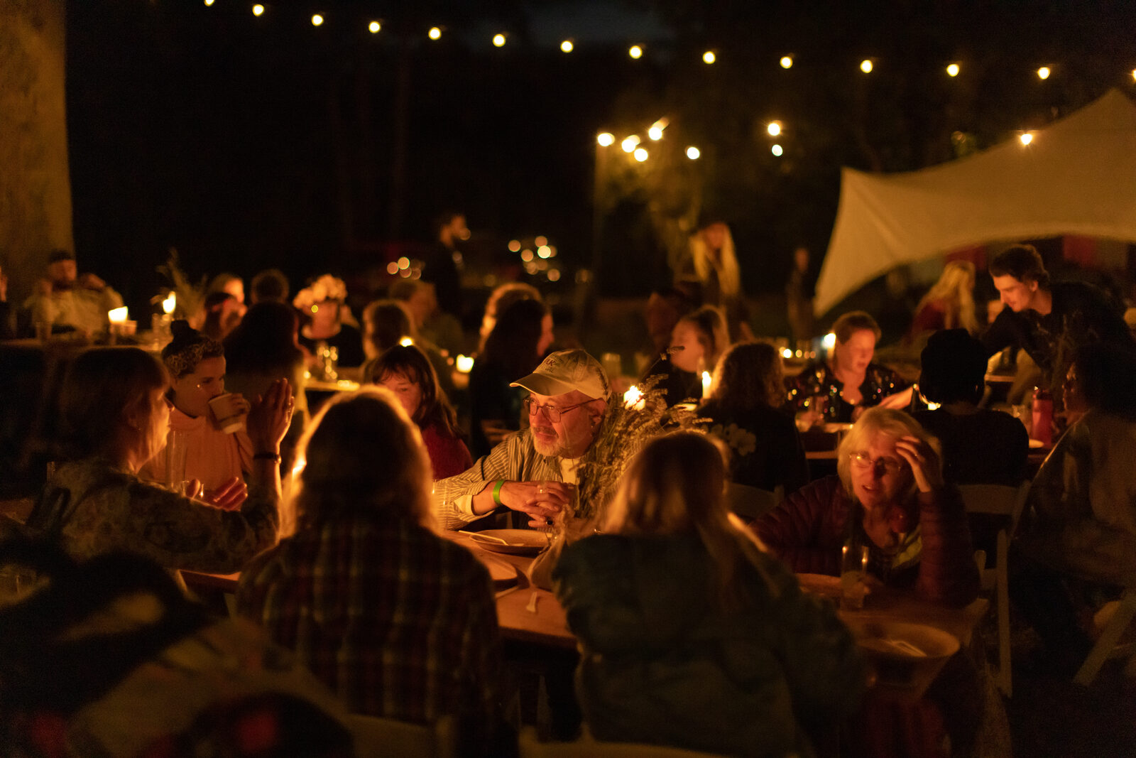 Candlelit dinner crowd gathered under canvas