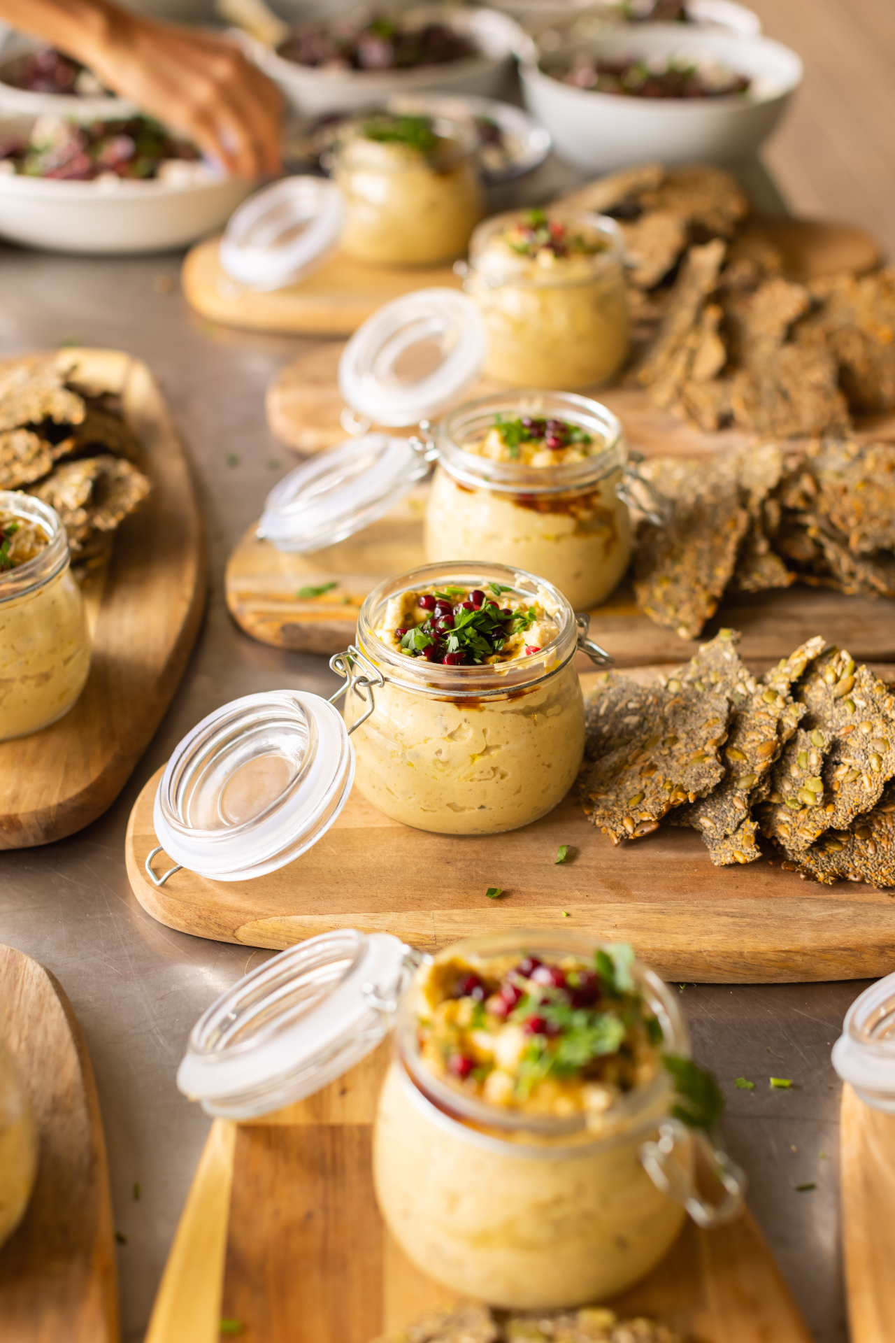 Hummus jars with seeded crackers laid out at woodland banquet