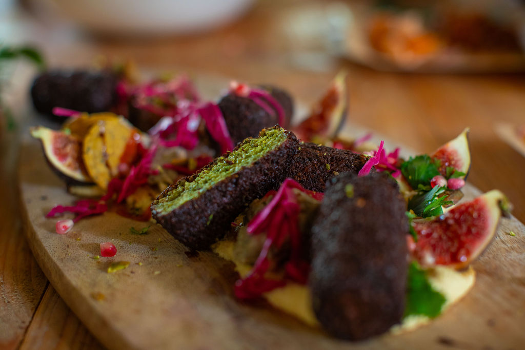 Pistachio kibbeh with figs, pickled cabbage and herbs on a wooden board