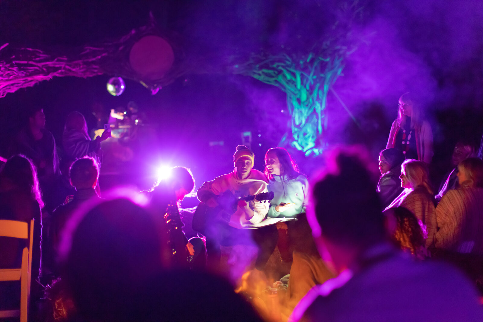 Smoky woodland stage with performers under purple light
